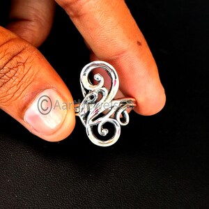 Puede incluir: Un anillo de plata con un diseño abstracto de espiral.