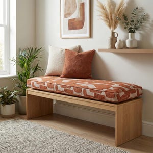 Peut inclure: Un banc en bois de chêne clair doté d'un coussin d'assise rectangulaire à motif abstrait orange brûlé et crème. Le banc est surmonté d'un coussin texturé couleur crème et d'un coussin orange brûlé avec un motif géométrique cousu.