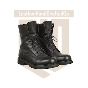 May include: A pair of black leather lace-up boots with a high-top design, featuring black eyelets, black laces, and a thick rubber sole. The text LeatherHandCraftedCo is visible at the top of the image, centred above the footwear.