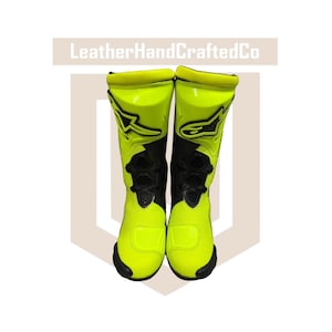 May include: A pair of neon yellow and black motorcycle boots. The boots have a tall design, with black accents and a prominent logo on the side. The boots are designed for protection and performance.