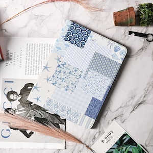 Puede incluir: Una funda para portátil de diseño patchwork en blanco y azul con una variedad de patrones que incluyen conchas marinas, palmeras y formas geométricas.