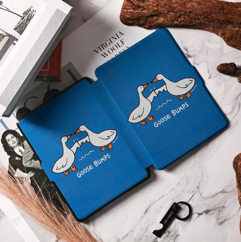 May include: Blue tablet case featuring a cartoon design of two white geese with orange feet and beaks, standing on a wave. The text "Goose Bumps" is below the geese. The case is open, revealing the interior.