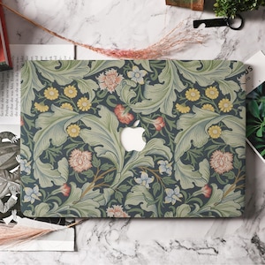 May include: A laptop case featuring a floral pattern in shades of green, blue, yellow, and pink. The design includes stylized leaves and flowers, with a white Apple logo cutout in the center. The case is on a marble surface.