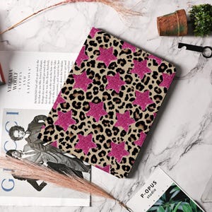 Può includere: Una custodia per laptop con un motivo leopardato rosa e marrone con stelle rosa glitterate.