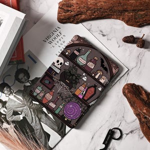 Pu&ograve; includere: Un'illustrazione in bianco e nero di uno scaffale di pozioni con varie bottiglie, barattoli e altri oggetti magici. Lo scaffale &egrave; decorato con una ragnatela, un teschio e una sfera di cristallo. L'illustrazione &egrave; su uno sfondo grigio scuro.