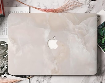 Peut inclure: Coque d'ordinateur portable avec un motif marbré blanc et beige. Elle présente une découpe pour le logo Apple. Le design est minimaliste et élégant, pour protéger un ordinateur portable.