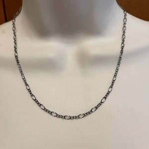 May include: A silver chain necklace with a delicate oval link design.