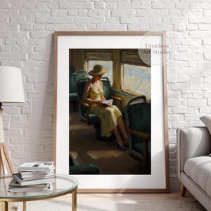 Può includere: Una stampa artistica incorniciata di una donna con un vestito e un cappello gialli che legge su un treno. L'opera d'arte è un dipinto con un'estetica vintage, con una vista soleggiata dalla finestra e sedili verdi. La stampa è di Timeless Art Studio.