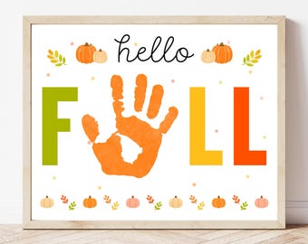 May include: A framed print with the words "hello FALL" in a playful font. The "F" is green, the handprint is orange, and the "LL" is yellow and orange. Pumpkins and leaves decorate the top and bottom.