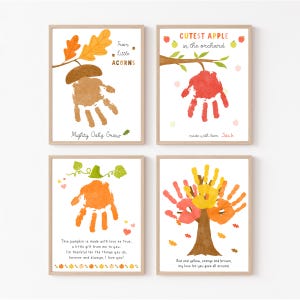 May include: Four framed art prints featuring handprint art. One print shows a brown acorn, another a red apple, a third an orange pumpkin, and the last a tree with red, yellow, and orange leaves. Each print has text.