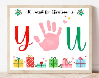 May include: A framed print with the text "All I want for Christmas is you." The word "you" is represented by a red "y", a pink handprint, and a green "u". Colorful gift boxes are at the bottom.