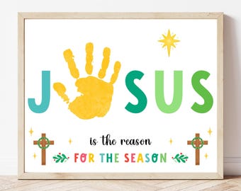 May include: A framed print with the word "JESUS" in teal and green, a yellow handprint, and the text "is the reason FOR THE SEASON." Includes a star, crosses, and decorative elements.