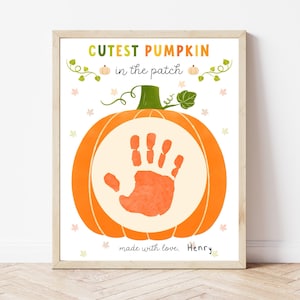 Puede incluir: Impresión enmarcada con una calabaza naranja, un tallo verde y una huella de mano en el centro. El texto "Cutest Pumpkin in the patch" está en la parte superior, y "made with love, Henry" en la inferior.
