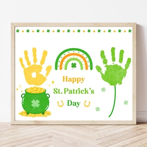 May include: A framed print with a St. Patrick's Day theme. It features a green pot of gold, a rainbow, handprints, shamrocks, and the text "Happy St. Patrick's Day" in a festive font. The print is in a wooden frame.