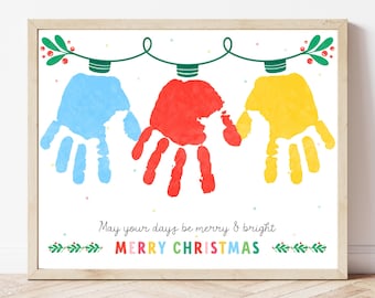 May include: A framed print with three handprints in blue, red, and yellow, styled as Christmas lights. The text "May your days be merry & bright" and "MERRY CHRISTMAS" are below the handprints. The print is in a wooden frame.