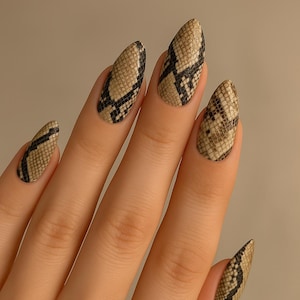 Könnte beinhalten: Nahaufnahme einer Hand mit fünf Nägeln, die mit einem braunen und schwarzen Schlangenhautmuster lackiert sind.