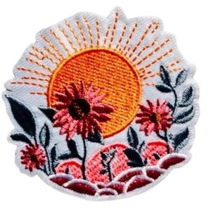 Könnte beinhalten: Gestickter Aufnäher mit einer leuchtend orangefarbenen Sonne mit Strahlen auf weißem Hintergrund. Rosa Blüten und grüne Blätter umgeben die Sonne und bilden ein Design mit Naturthema. Der Aufnäher hat einen dekorativen, genähten Rand.