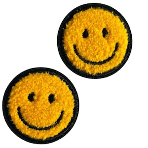 Könnte beinhalten: Zwei gelbe Smiley-Aufnäher mit schwarzen Umrandungen. Die Aufnäher haben ein strukturiertes, flauschiges Aussehen und zeigen schwarze Augen und ein gebogenes Lächeln. Die Aufnäher sind kreisförmig und vor weißem Hintergrund.