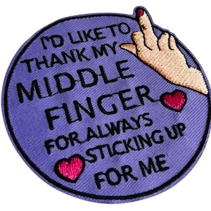 Könnte beinhalten: Gestickter Aufnäher mit lila Hintergrund und schwarzem Text, der lautet: "I'D LIKE TO THANK MY MIDDLE FINGER FOR ALWAYS STICKING UP FOR ME." Eine Hand mit erhobenem Mittelfinger befindet sich in der oberen rechten Ecke, und zwei rote Herzen sind auf dem Aufnäher.