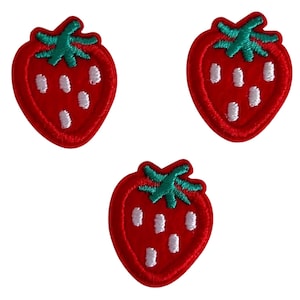 Könnte beinhalten: Drei gestickte Erdbeer-Patches. Jeder Patch zeigt eine rote Erdbeere mit weißen Samendetails und einem grünen Stiel. Die Patches befinden sich auf weißem Hintergrund.