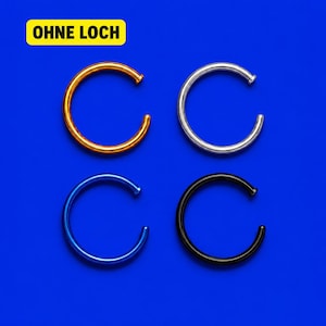 Könnte beinhalten: Vier kreisförmige Ringe in Gold, Silber, Blau und Schwarz. Jeder Ring hat ein kleines flaches Ende und eine Öffnung. Ein gelbes rechteckiges Etikett in der oberen linken Ecke enthält den schwarzen Text OHNE LOCH.