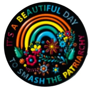 Könnte beinhalten: Ein runder, schwarzer Anstecker mit einem farbenfrohen Regenbogen- und Blumendesign. Der Anstecker zeigt den Text "It's a beautiful day to smash the patriarchy" in einem kreisförmigen Muster. Der Regenbogen hat orange, gelbe, grüne und blaue Streifen.