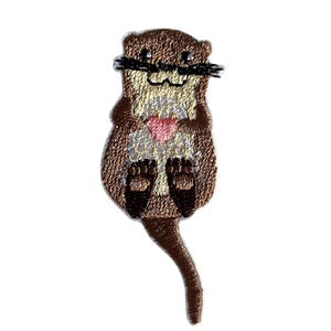 Könnte beinhalten: Gestickter Aufnäher einer Cartoon-Otter, die ein rosa Herz hält. Der Otter ist braun mit einem beigen Bauch, schwarzen Schnurrhaaren und schwarzen Füßen. Der Aufnäher ist zum Aufbügeln oder Aufnähen auf Stoff gedacht.