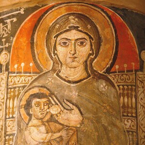 May include: A Byzantine-style fresco painting depicting a religious figure with a halo, holding a child. The figures are painted in muted tones of brown, beige, and gray, with a red halo. The artwork is set against a background of architectural elements.