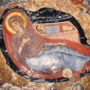 May include: A religious fresco depicting a woman with a halo, cradling a baby in a manger. The artwork features a red and brown color palette, with figures in the background. The style is reminiscent of Byzantine art.