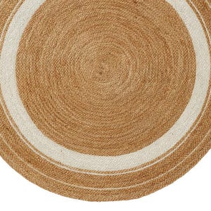 May include: A round jute rug with a natural brown color and a white border. The rug is made of woven fibers and has a circular design. The rug is suitable for indoor use.