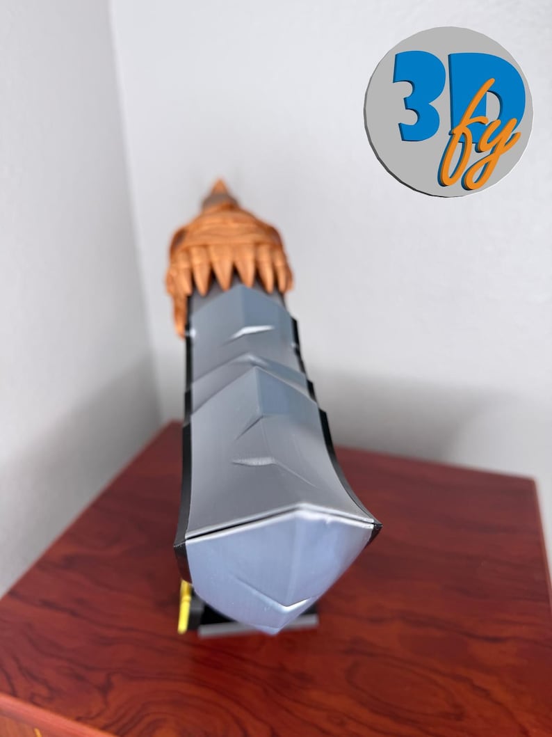 May include: A 3D-printed sword with a gray blade and a brown hilt. The sword has a geometric design and is displayed on a wooden surface. The logo "3D by" is visible in the background.