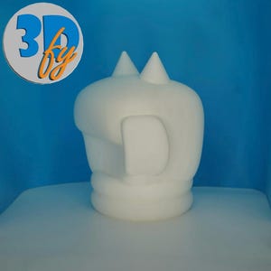 May include: A white 3D-printed sculpture of a stylized head with two conical protrusions on top and a large, curved ear-like shape on the side. The sculpture is on a white surface with a blue background. The logo "3D by" is in the upper left corner.