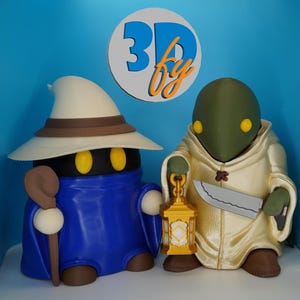 May include: Two 3D-printed figurines of video game characters. One is a black mage in a blue robe and white hat, holding a staff. The other is a green-skinned character in a cream-colored robe, holding a lantern and a knife. A sign above reads "3D by".