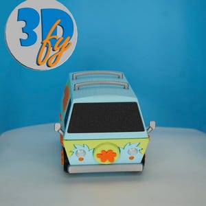 May include: A miniature, colorful van with a light blue roof and a black windshield. The van has orange and green accents, with a flower emblem on the front. The image includes the text "3D by" in blue and orange.