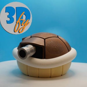 May include: A 3D-printed brown Koopa shell with a white trim and a silver cannon. The shell is set against a blue background. The logo "3D by" is in the upper left corner.