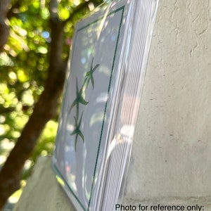 May include: A boxed set of eight blank greeting cards and envelopes featuring a green starfish design. The cards are packaged in a clear plastic sleeve.