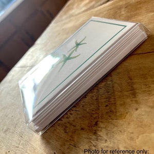May include: A boxed set of eight blank greeting cards with envelopes. The cards feature a green and white design with a starfish motif.