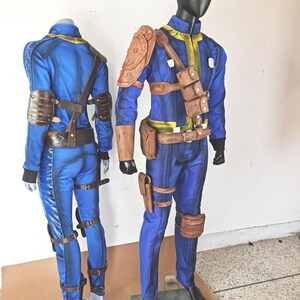 May include: Two blue and brown jumpsuit costumes with leather straps and buckles. The costumes are on mannequins.