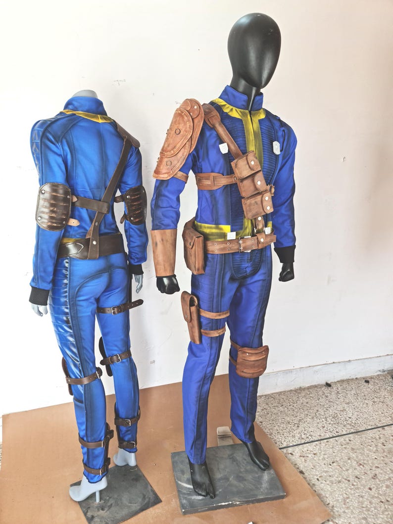 May include: Two blue and brown jumpsuit costumes with leather straps and buckles. The costumes are on mannequins.