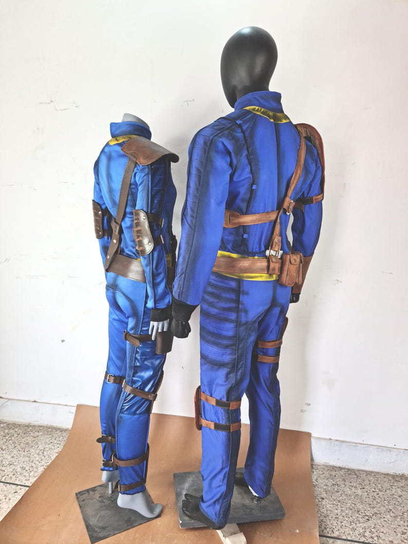 May include: Two blue and brown jumpsuits with yellow accents. The jumpsuits have straps and buckles. The jumpsuits are on mannequins.