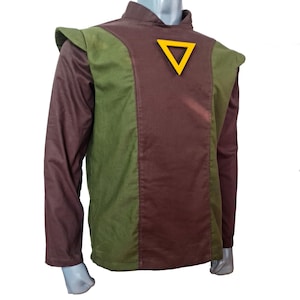 May include: A costume top with a brown and green color block design. The long-sleeved top features a high collar and a yellow triangle emblem. The shoulders have a padded design. The costume is displayed on a mannequin.
