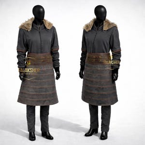 Könnte beinhalten: Zwei Schaufensterpuppen präsentieren ein dunkelgraues Kostüm. Das Outfit umfasst eine Jacke mit Pelzkragen, einen Gürtel und einen rockartigen Unterteil. Das Kostüm wird durch dunkle Hosen und Stiefel vervollständigt. Das Logo "FALAKSHER TOPSTITCH" ist auf dem Gürtel zu sehen.