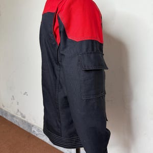 Pode incluir: Casaco preto e vermelho com gola alta e dois bolsos frontais. A parte superior do casaco e a gola s&atilde;o vermelhas, enquanto o corpo &eacute; preto. O casaco tem bainha e punhos canelados.