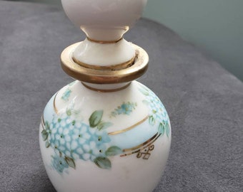 May include: A white porcelain perfume bottle with a gold trim and a blue and white floral design.