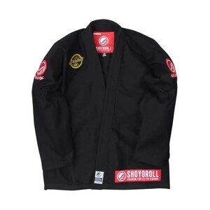 Pode incluir: Kimono de Jiu-Jitsu preto com patches bordados em vermelho e amarelo. O kimono apresenta o nome da marca "SHOYOROLL" no peito, mangas e bainha inferior. Feito de um material durável, é projetado para treinamento em artes marciais.