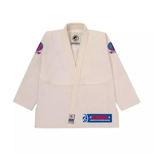 Pode incluir: Uniforme de Jiu-Jitsu branco sujo com gola em V e mangas compridas. O uniforme apresenta patches com logotipos circulares nos ombros e um patch retangular com texto na parte inferior. Projetado para grappling.