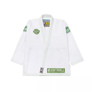 Puede incluir: Gi blanco de Jiu-Jitsu con logotipos bordados en verde y negro. El gi presenta el texto "Shoyorroll" y "Premium Fine Fitted Kimonos".
