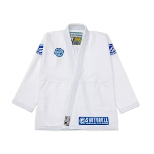 Pode incluir: Gi branco de Jiu-Jitsu com detalhes azuis e o texto "Shoyoroll Premium Line Fitted Kimonos" na parte inferior direita.