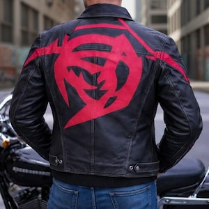 May include: Black leather jacket featuring a striking red graphic on the back. The jacket has a classic biker design with a collar, zip, and button details. The graphic is a bold, abstract shape.