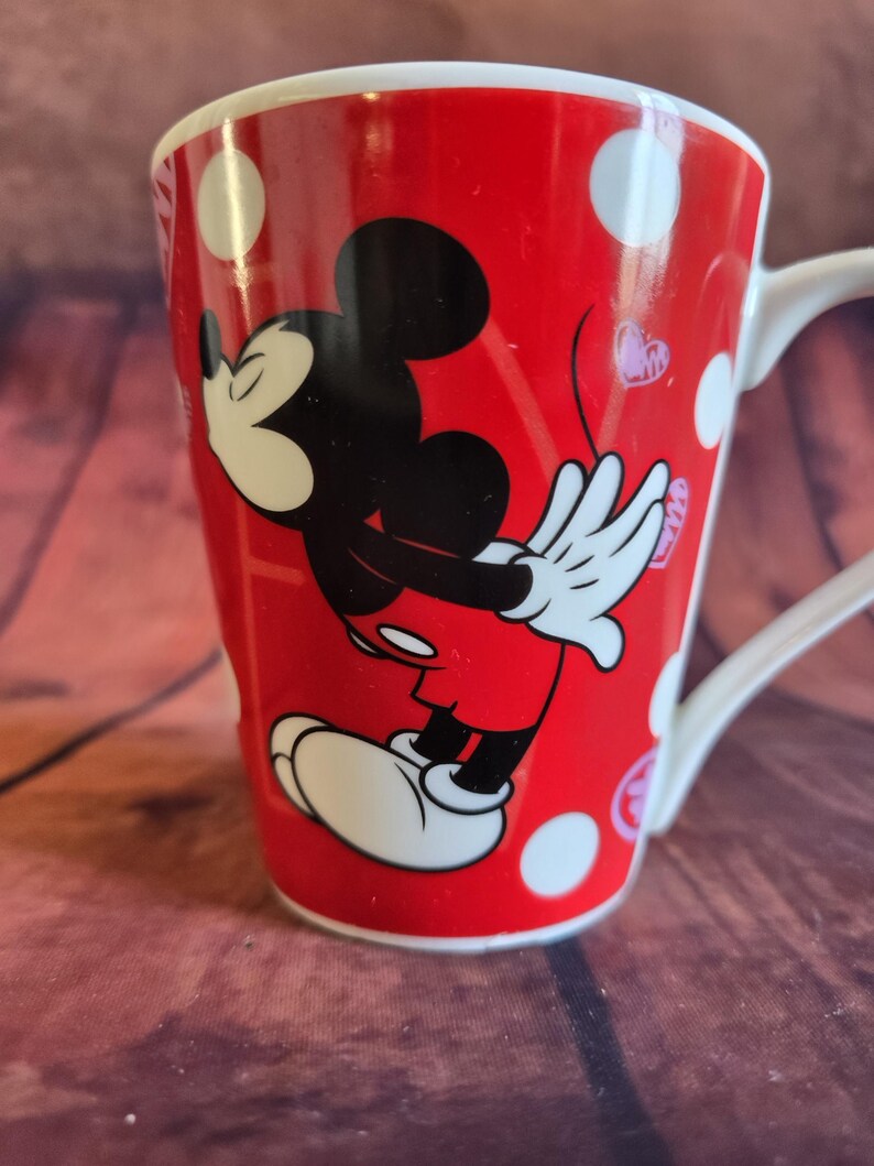 Puede incluir: Taza de cer&aacute;mica roja con Mickey Mouse. La taza tiene un asa blanca y est&aacute; decorada con lunares blancos y peque&ntilde;os corazones rosas. Una adici&oacute;n divertida y colorida a la colecci&oacute;n de cualquier fan de Disney.